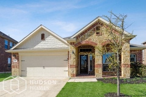 a brick house with a white garage door and a tree in the yard